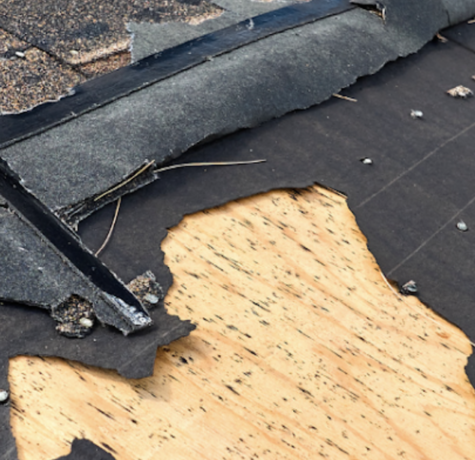 Damaged roof with missing and ripped shingles exposing the underlayment.