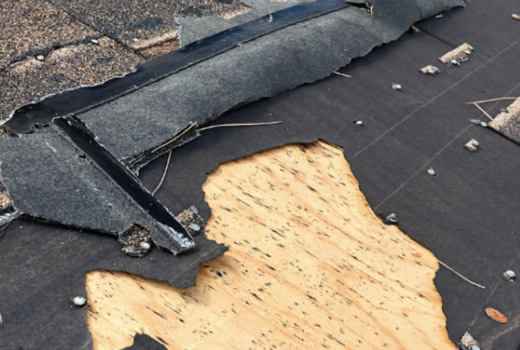 Damaged roof with missing and ripped shingles exposing the underlayment.