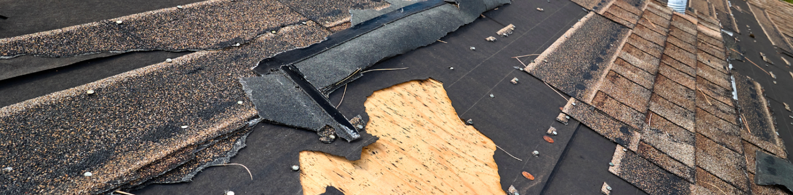 Damaged roof with missing and ripped shingles exposing the underlayment.